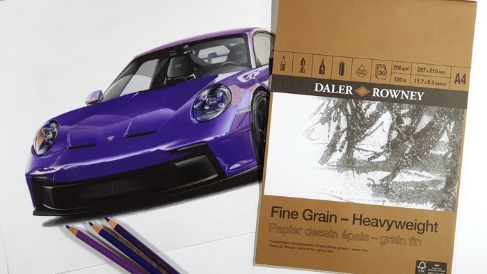 drawing of a car porsche 992 gt3 in ultraviolet next to a pad of daler & rowney fine grain heavyweight paper - best paper for oil-based colored pencils